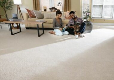 Couple playing with dog sitting on carpet floor | Kelly's Carpet Omaha